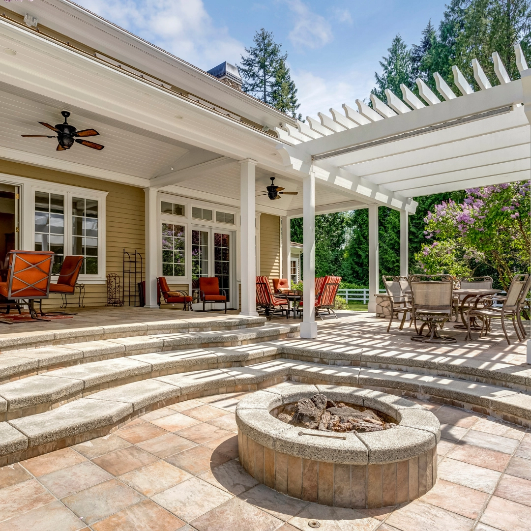 Stone patio with built in fire pit, steps, pergola, and outdoor seating at a residential home, showcasing professional hardscaping and outdoor living services.